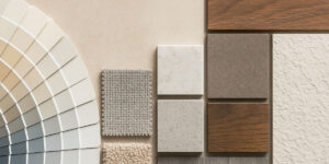 A flat lay of paint swatches, fabric samples, and material tiles in neutral tones showcasing design color and texture combinations.