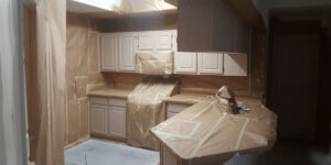 A kitchen fully masked with paper and tape in preparation for painting or refinishing.