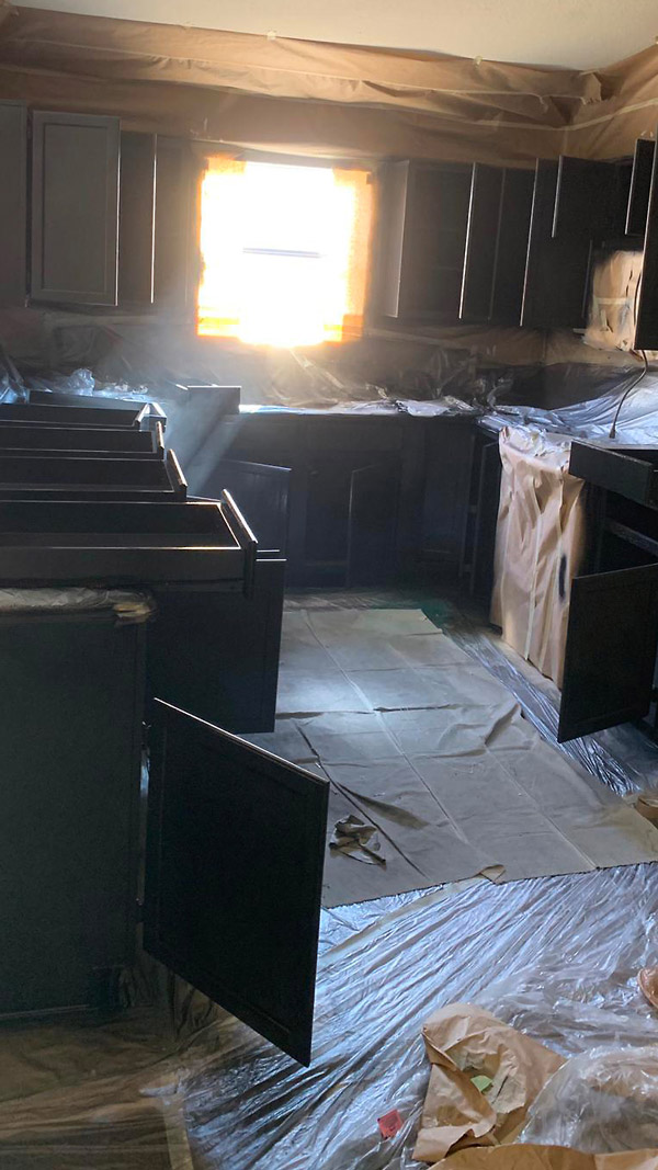 A kitchen in progress with cabinets covered and masked off during a refinishing project.