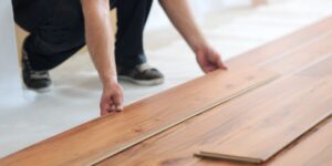 A person installing wood flooring planks in a home, representing flooring selection, home renovation, durability, interior upgrades, and practical living solutions.