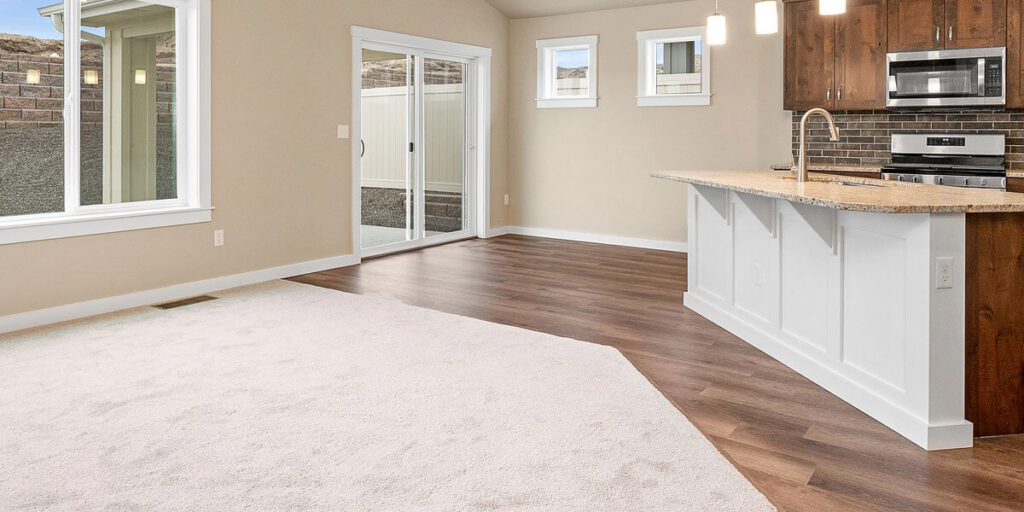 Open-concept kitchen and living area featuring carpet and durable wood-look flooring.