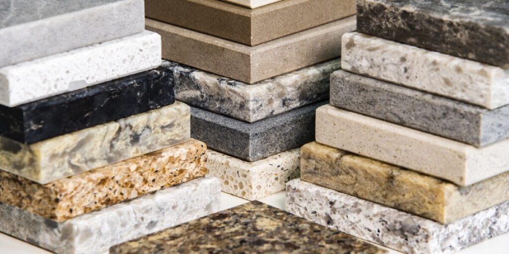 Stacked samples of various countertop materials showing different colors, patterns, and textures.